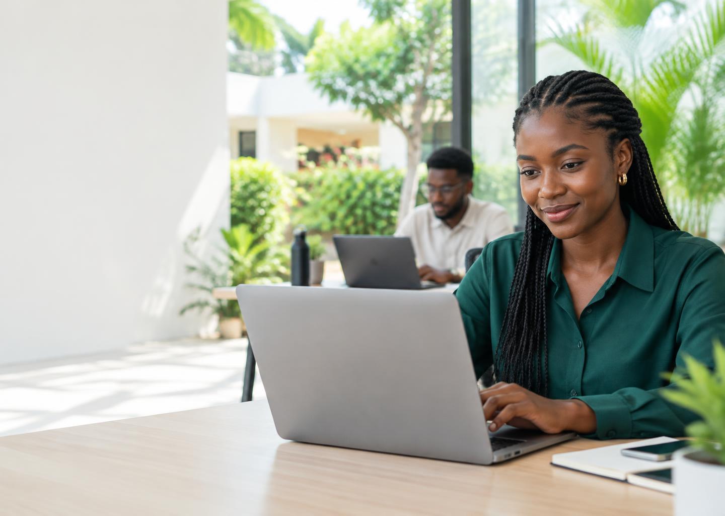 Une professionnelle africaine travaille sur son ordinateur dans un espace lumineux.